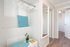 ein weißes Zimmer mit einem Tisch und einem Spiegel in der Unterkunft Apartmenthaus "Kiki", Wohnung "Traumbude" in Heiligenhafen + 31 Fotos