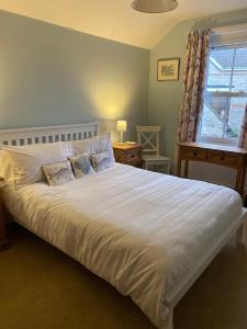 a large white bed in a bedroom with a window at Gretenham B&B in Swanage