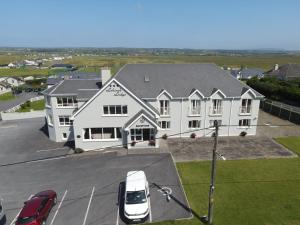 a large white building with a car parked in a parking lot at Lehinch Lodge in Lahinch