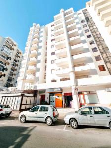 two cars parked in a parking lot in front of a building at Apartment Praia Rocha Candimar Sunflower in Portimão