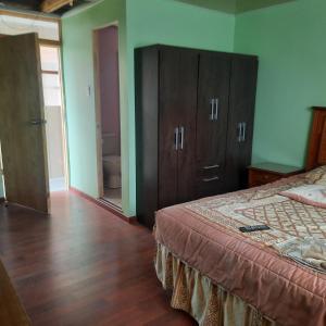 a bedroom with a bed and wooden floors and green walls at Hospedaje La ruta Los Angeles in Los Ángeles