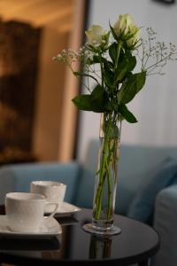 a vase of flowers on a table with two cups at Entre Nous Le Du Bellay in Saumur