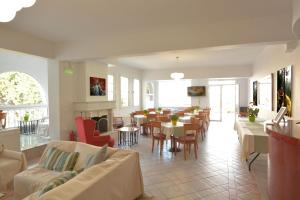 Olympus Hotel Villa Drosos في لتوخورو: غرفة معيشة مع طاولات وكراسي وغرفة طعام