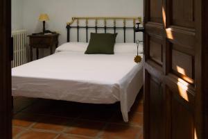 um quarto com uma cama branca e uma almofada verde em Gran Casa Rural La Vendimia 