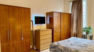 ロンドンにあるSloane Square Apartmentsのベッドルーム1室(ベッド1台付)、大きな木製キャビネットが備わります。