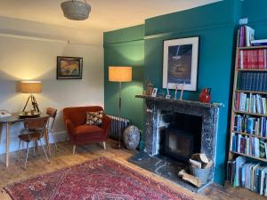 a living room with a fireplace and a book shelf with books at Frizenham Farmhouse in Little Torrington
