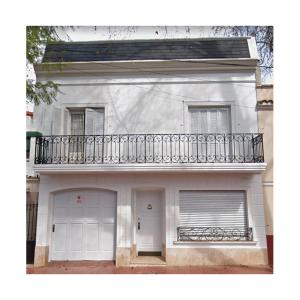 a white house with a balcony and a garage at La Rufina B&B in Mendoza
