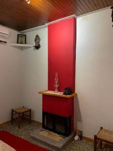 a room with a fireplace with a red wall at Villa Lochia - Καλημέρι in Elafopídima