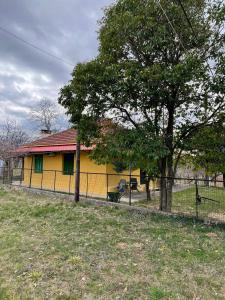 a yellow house with a fence and a tree at Villa Lochia - Καλημέρι in Elafopídima