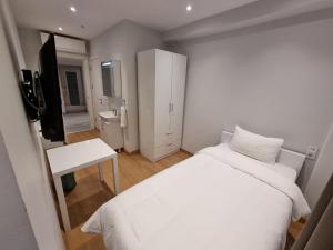 10m2 Hotel في إسطنبول: غرفة نوم بيضاء فيها سرير وتلفزيون