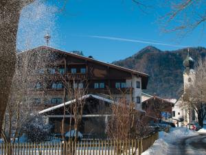 un bâtiment dans la neige avec des montagnes en arrière-plan dans l'établissement Hotel-Gasthof Sperrer, à Grassau