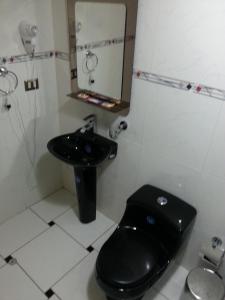 a bathroom with a black toilet and a sink at Padama in Lima