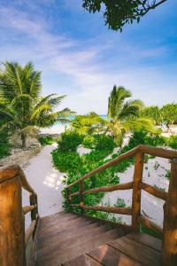 uma ponte de madeira que leva a uma praia com palmeiras em Sunshine Bay Hotel Zanzibar em Matemwe