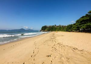 una playa con huellas en la arena y el océano en Hostel 3.5 en Ubatuba