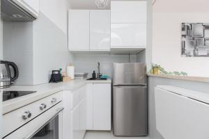 Una cocina con gabinetes blancos y un refrigerador de acero inoxidable. en ShortStayPoland Chłodna (B74), en Varsovia