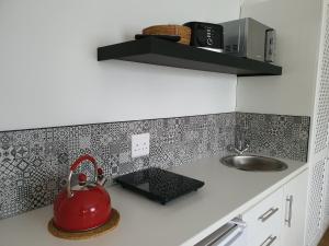 a kitchen with a sink and a red tea kettle at Plett57 - Self Catering - Room No2 in Plettenberg Bay
