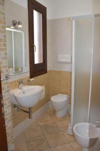 a bathroom with a sink and a toilet and a mirror at Hotel Sikania in San Vito lo Capo