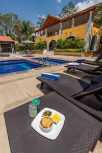 a table with a plate of food next to a pool at Hotel Hacienda Montesinos in Morelia