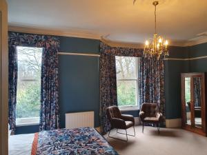 a bedroom with a bed and two chairs and windows at Bronte Guest House in York