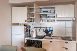 a kitchen with white cabinets and a white refrigerator at LA BRIOSA-INFINITYHOLIDAYS in Costa Paradiso +30 photos