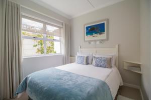 a white bedroom with a bed and a window at South Point Guest Lodge in Agulhas