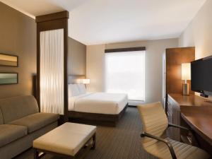 a small hotel room with a bed and a couch at Hyatt Place San Jose Pinares in San José