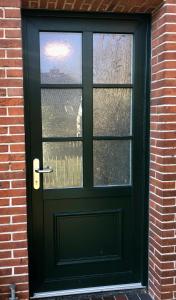 a green door with a window in a brick building at Paradiesje 2 in Leer