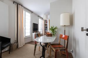 uma sala de estar com uma mesa e cadeiras e uma televisão em Luxe Atelier bail mobilité Saint germain des Près em Paris