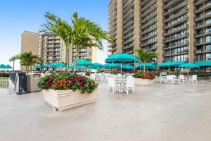 a patio with tables and chairs and blue umbrellas at Sea Colony -- 112 Georgetowne in Bethany Beach