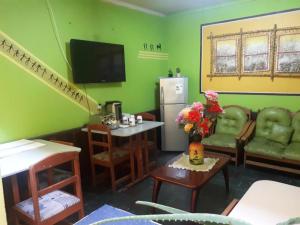 a living room with green walls and a kitchen with a refrigerator at Hostal Copa Arica in Arica