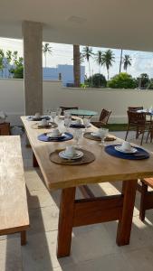 une longue table en bois avec des assiettes et des verres dessus dans l'établissement Santo Mar São Miguel do Gostoso, à São Miguel do Gostoso