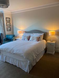 a bedroom with a large white bed and a chair at Gretenham B&B in Swanage