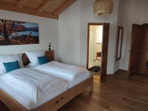 a bedroom with a bed with white sheets and blue pillows at Landhaus Hutter in Bad Heilbrunn