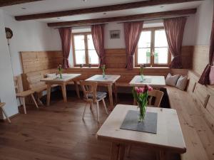 una stanza con tavoli, sedie e finestre di Landhaus Hutter a Bad Heilbrunn