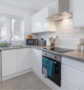 a kitchen with white cabinets and a stove top oven at Air Host and Stay - Beautiful brand new 3 bedroom house sleeps 7 minutes from LFC - 10 in Liverpool