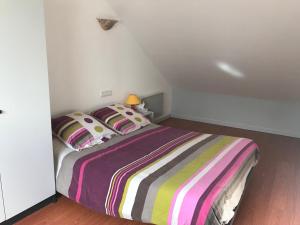 a bedroom with a bed with a colorful striped blanket at La Coudraie: Loft sauna/jacuzzi privatif à la campagne in Saint-Pardoux-le-Vieux