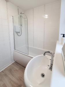 a white bathroom with a shower and a sink at 3 bedroom house Amazon M90 Dunfermline Edinburgh in Fife