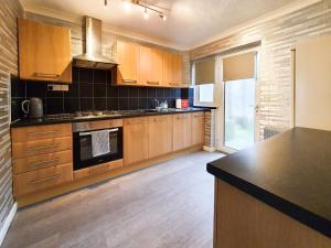 a kitchen with wooden cabinets and a black counter top at 3 bedroom house Amazon M90 Dunfermline Edinburgh in Fife