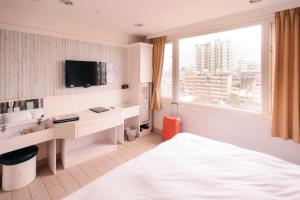 a bedroom with a bed and a desk and a tv at Kiwi Express Hotel - Zhong Zheng Branch in Taichung