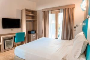 a bedroom with a large bed and a tv at AQUA SARDINIA boutique hotel in Budoni