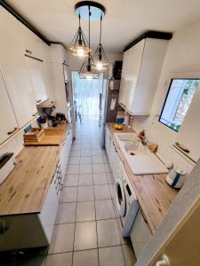 - une cuisine avec des placards blancs et des comptoirs en bois dans l'établissement Cap Capistol Golf, appartement 2 chambres, au Cap d'Agde