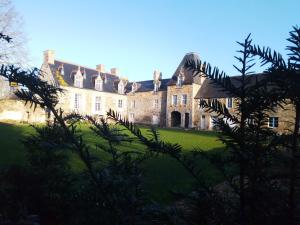 um velho castelo com um relvado verde em frente em Domaine du Manoir de Vains em Vains