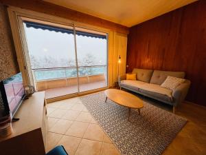 ein Wohnzimmer mit einem Sofa, einem Tisch und einem Fenster in der Unterkunft Appartement rénové à 200m de la plage + garage in Embrun