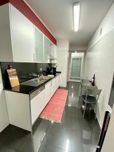 uma cozinha com armários brancos e um tapete vermelho em Concordia Apartment no Funchal