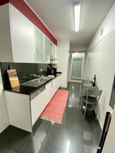 een keuken met witte kasten en een rood tapijt bij Concordia Apartment in Funchal