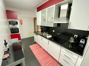 a kitchen with white cabinets and black counter tops at Concordia Apartment in Funchal