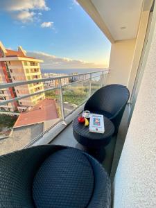 uma varanda com 2 cadeiras e uma mesa com um relógio em Concordia Apartment no Funchal