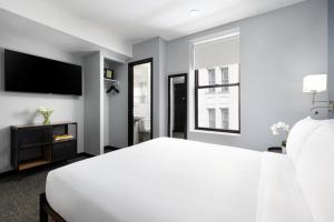 um quarto branco com uma cama e uma tv em OYO Times Square em Nova Iorque