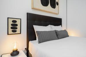 Schlafzimmer mit einem Bett mit einem schwarzen Kopfteil und einer Lampe in der Unterkunft WHome | Paz Downtown Apartment #2 in Lissabon