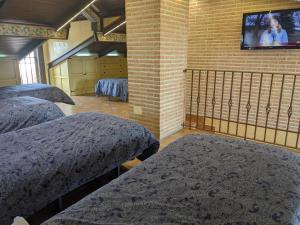 - une chambre avec 2 lits et une télévision sur un mur en briques dans l'établissement Villa El Rosal del Pozo, a 5 minutos de Puy du Fou, à Layos